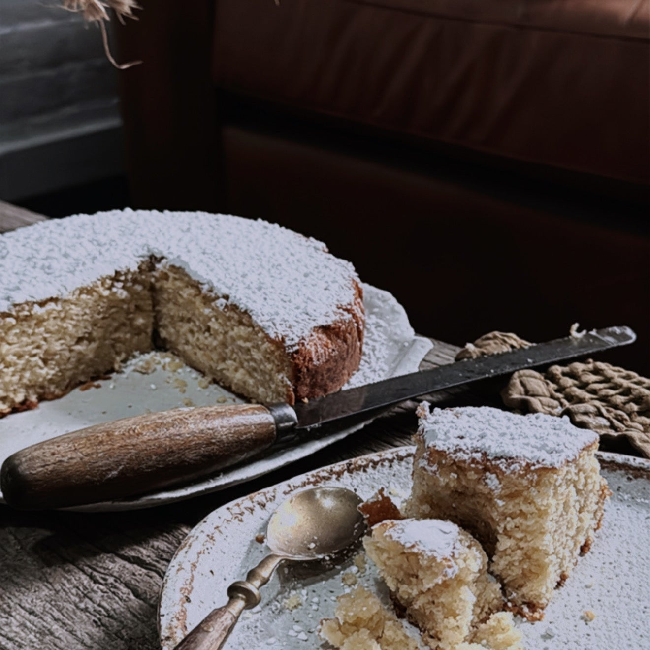 Sliced cake on a plate with a spoon, placed on a wooden table.