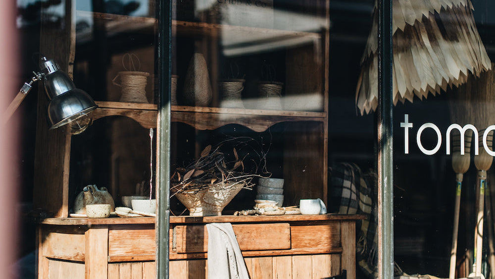 Store window display with wooden furniture and decor items at Tomolly, Carcoar.