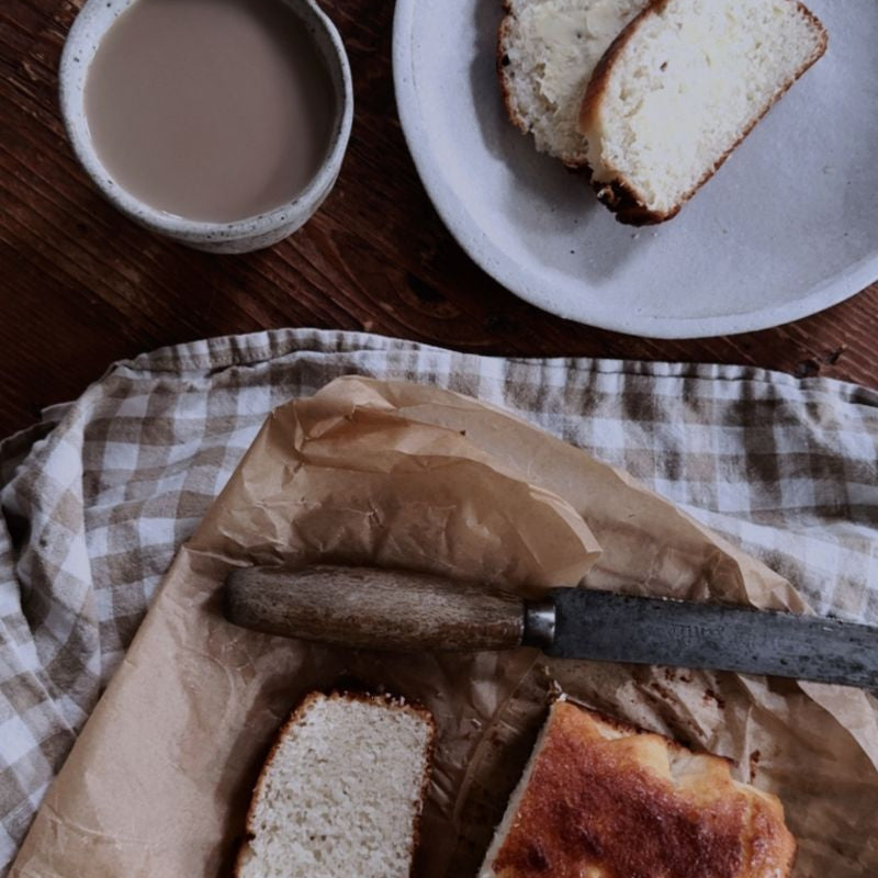 Freshly baked Coconut Bread served on ceramic plate with a cup of tea.