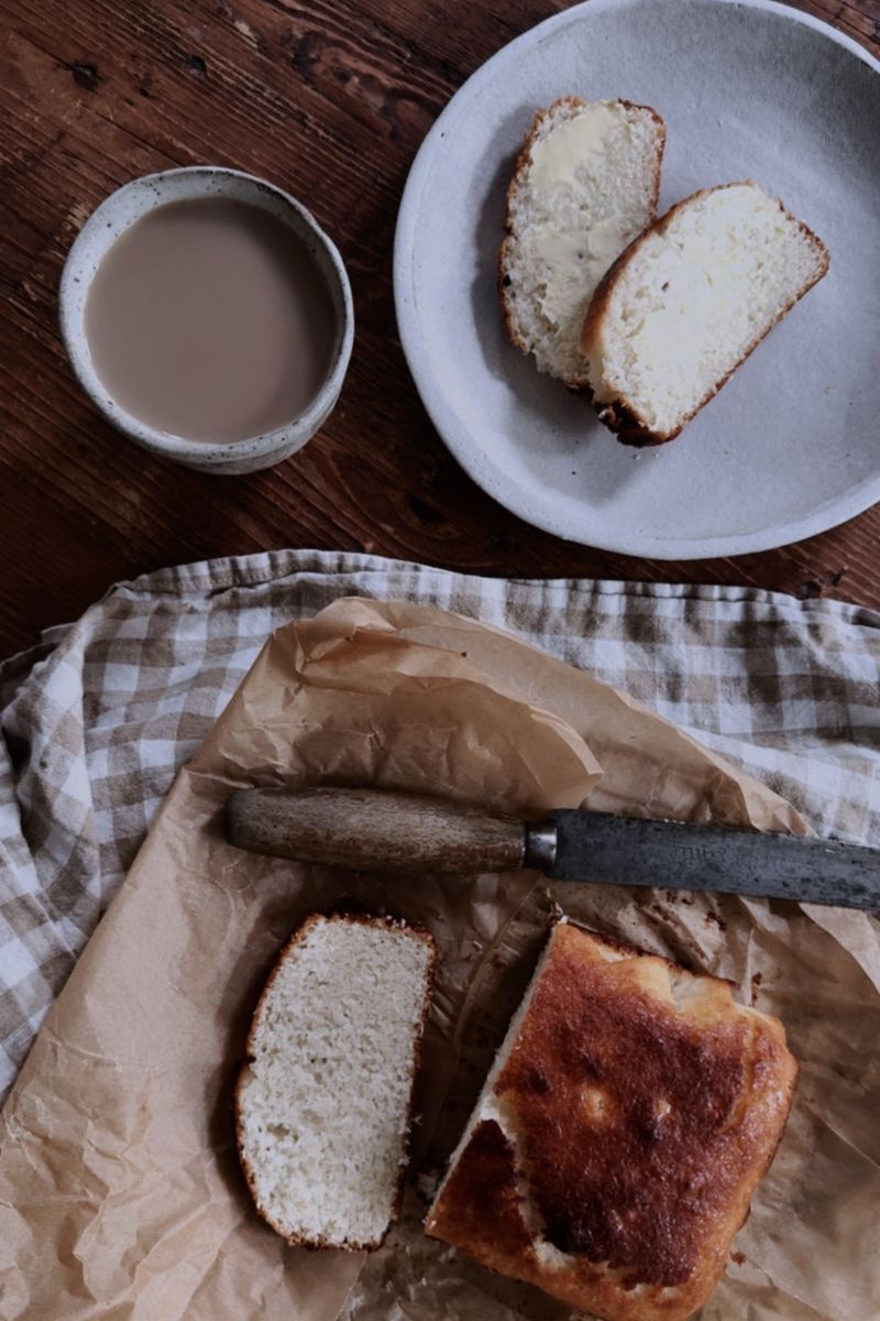 Freshly baked Coconut Bread served on ceramic plate with a cup of tea.